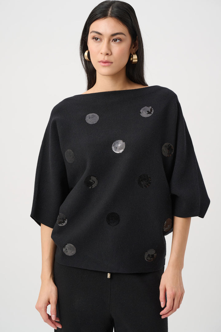 Woman wearing a black top with circular patterns on a white background