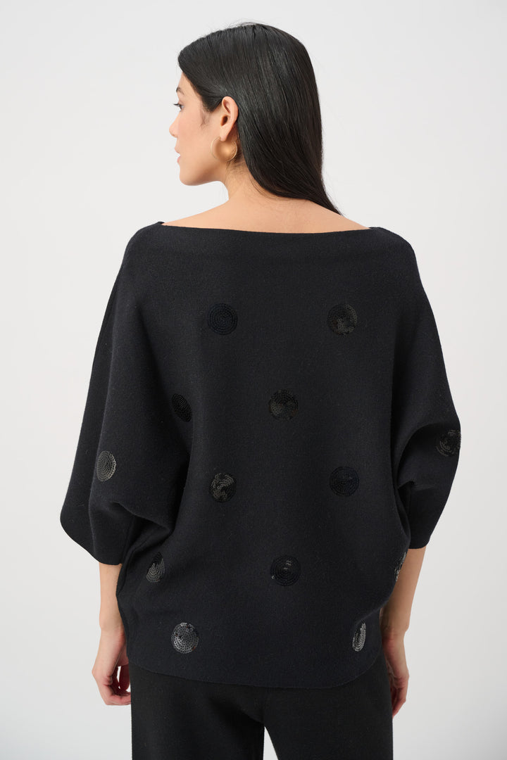 Black sweater with button details worn by a person on a white background