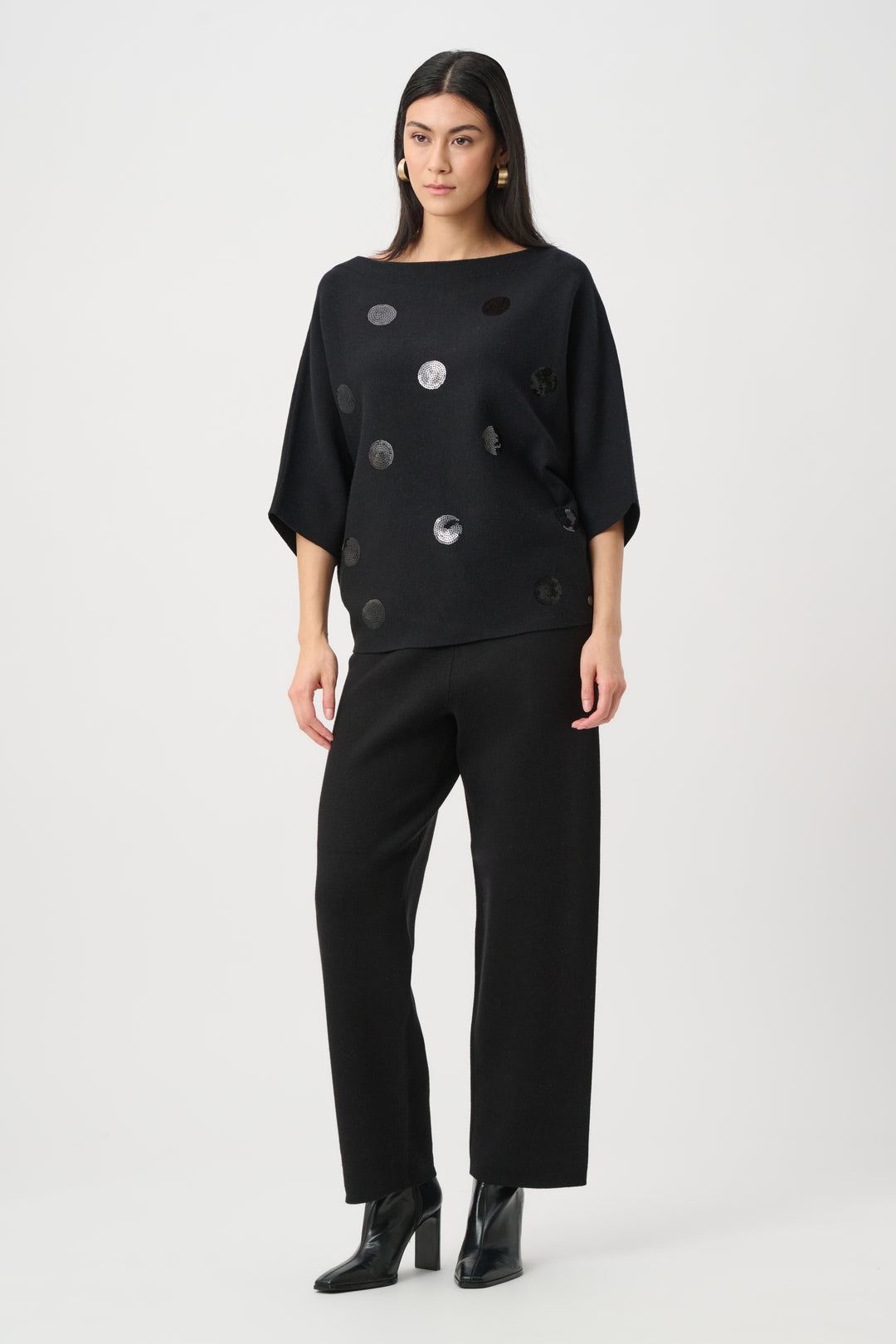 Woman wearing a black outfit with button details on a white background