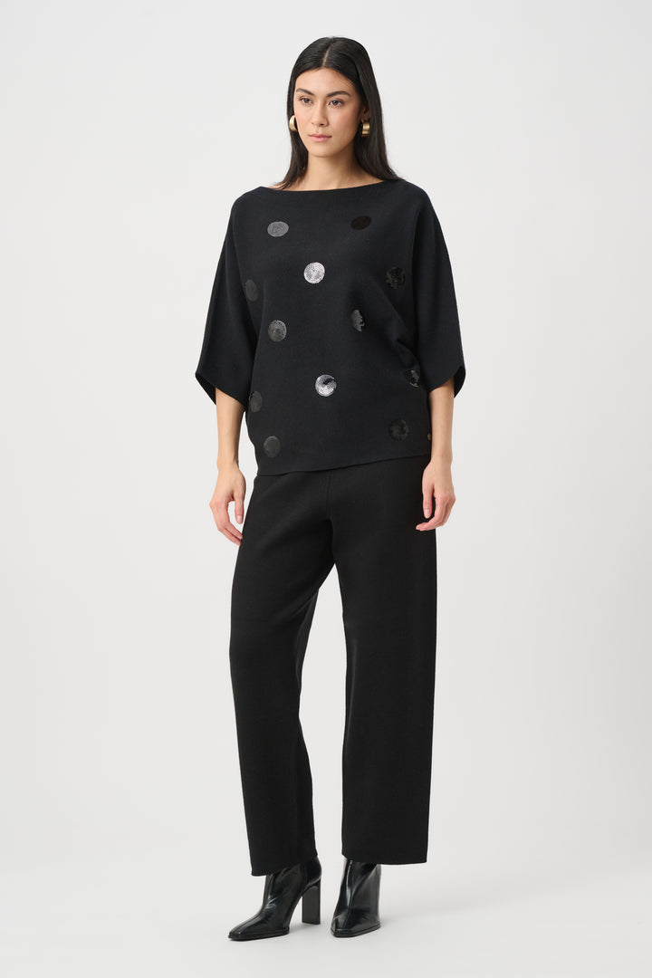 Woman wearing a black outfit with button details on a white background