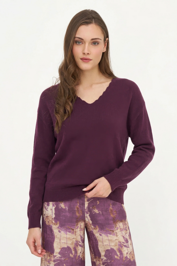 Woman wearing a purple sweater and patterned pants on a white background