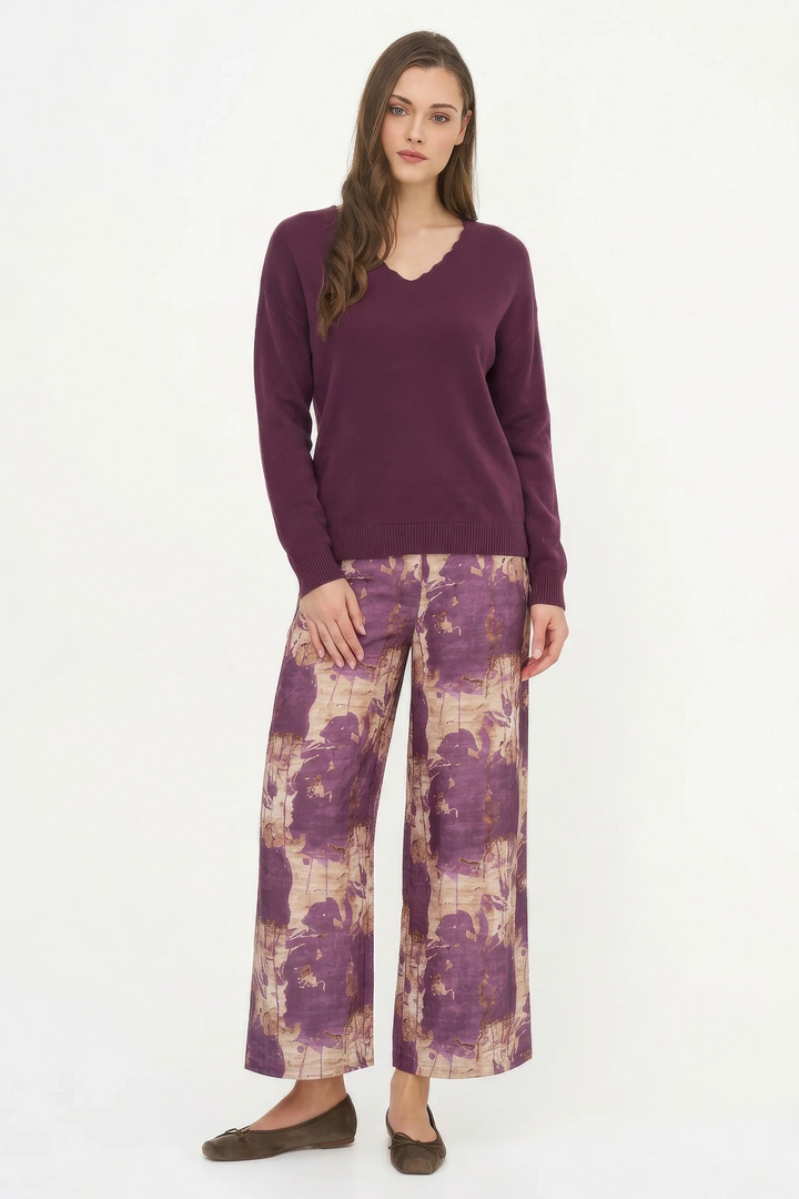 Woman wearing a purple sweater and patterned pants on a white background