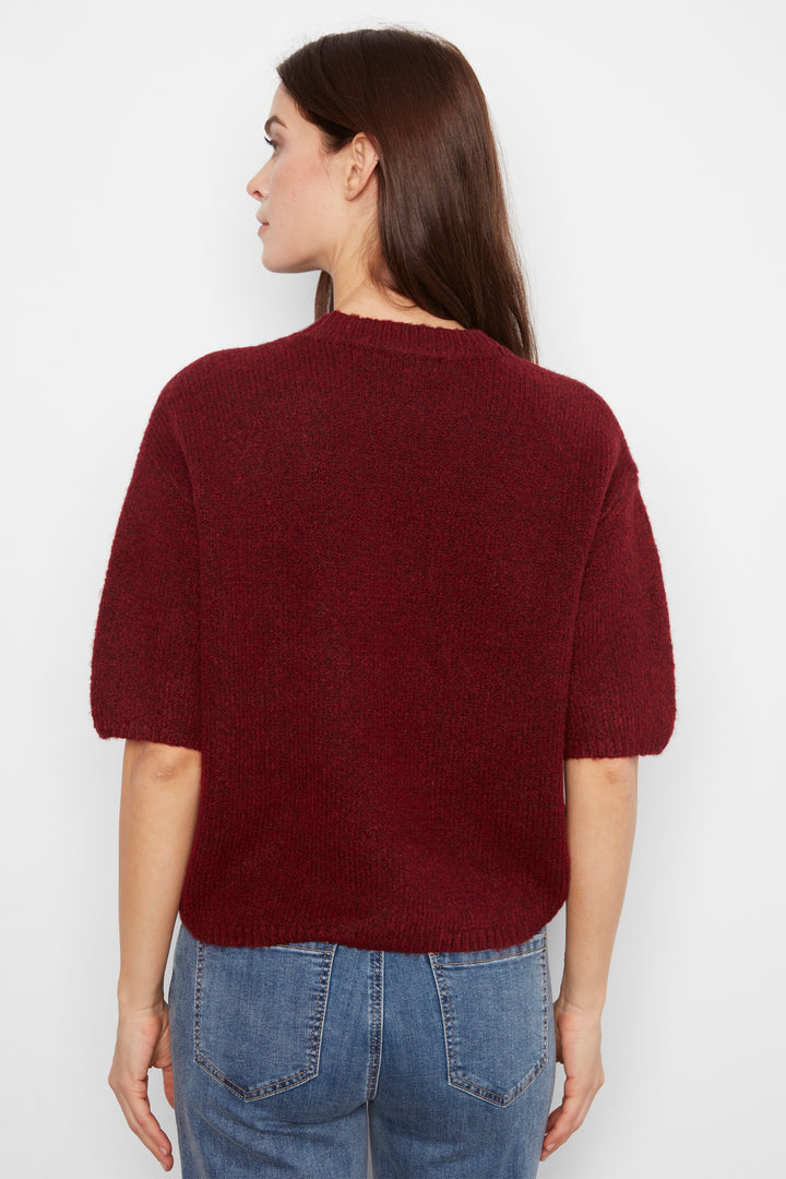 A woman shown from the back wearing a short-sleeve, crew-neck knit sweater in a deep burgundy red, paired with blue jeans, against a plain white background.