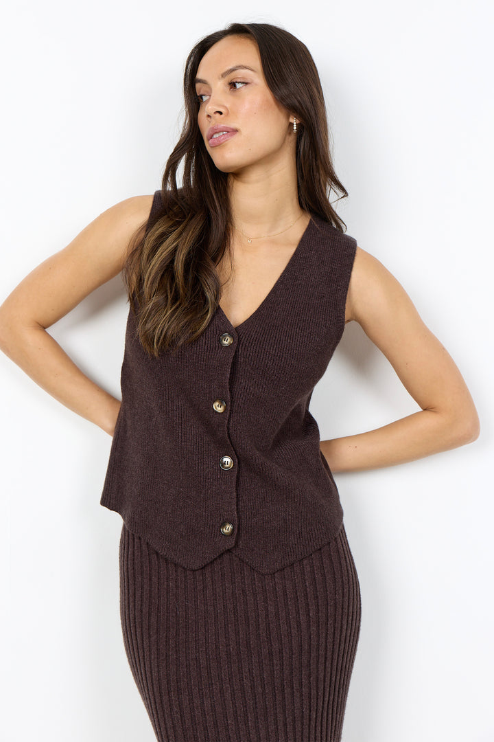 A woman modeling a sleeveless ribbed knit vest in dark brown with three front buttons, paired with a matching ribbed knit skirt, against a plain white studio background.