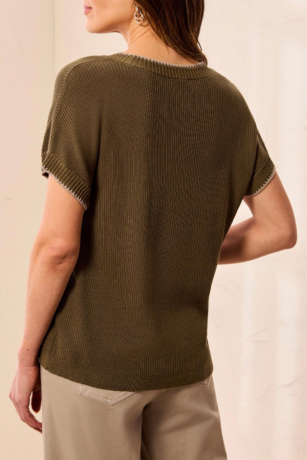 Woman wearing a brown knitted sweater against a plain background