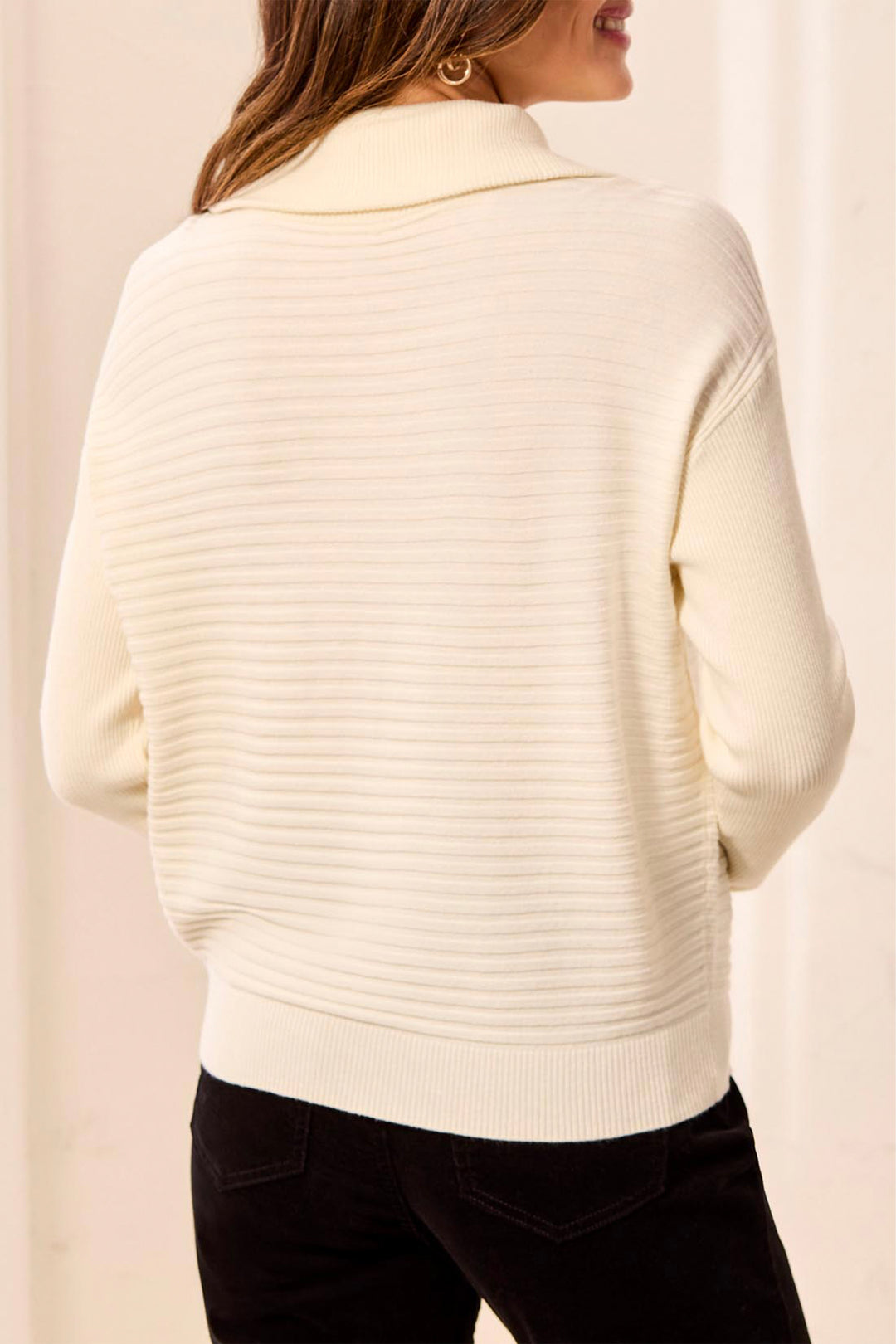 White ribbed sweater worn by a person on a beige background