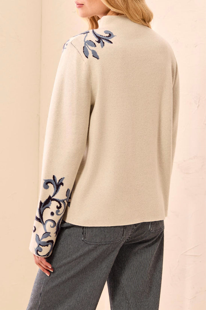 Beige sweater with floral embroidery on sleeves and neckline against a beige background