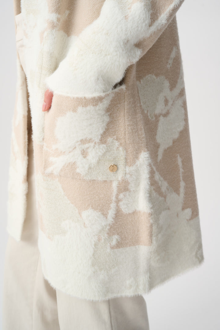 Beige cardigan with floral pattern and white fur trim on a plain background
