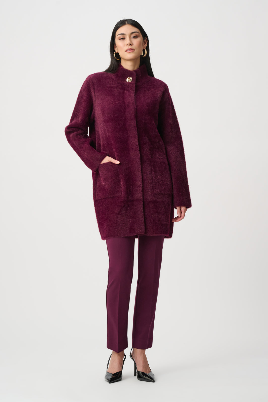 Woman wearing a burgundy coat and pants on a white background