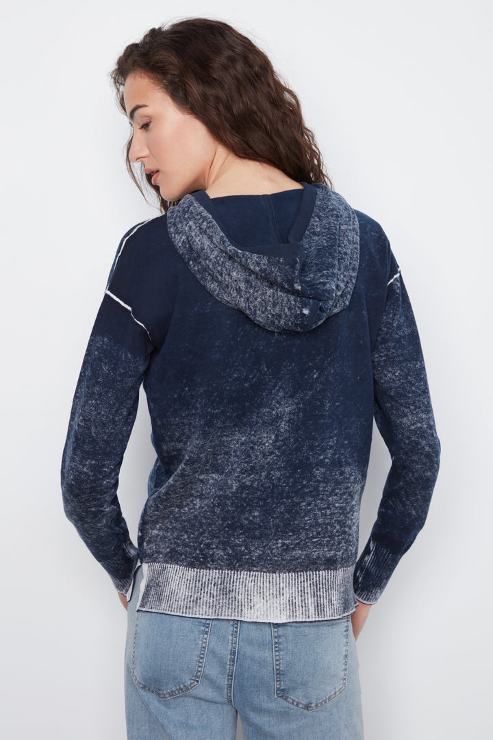 A woman shown from the back wearing a navy blue hooded sweatshirt with a marled lighter blue hood and light gray ribbed trim, paired with light blue jeans against a plain white background.