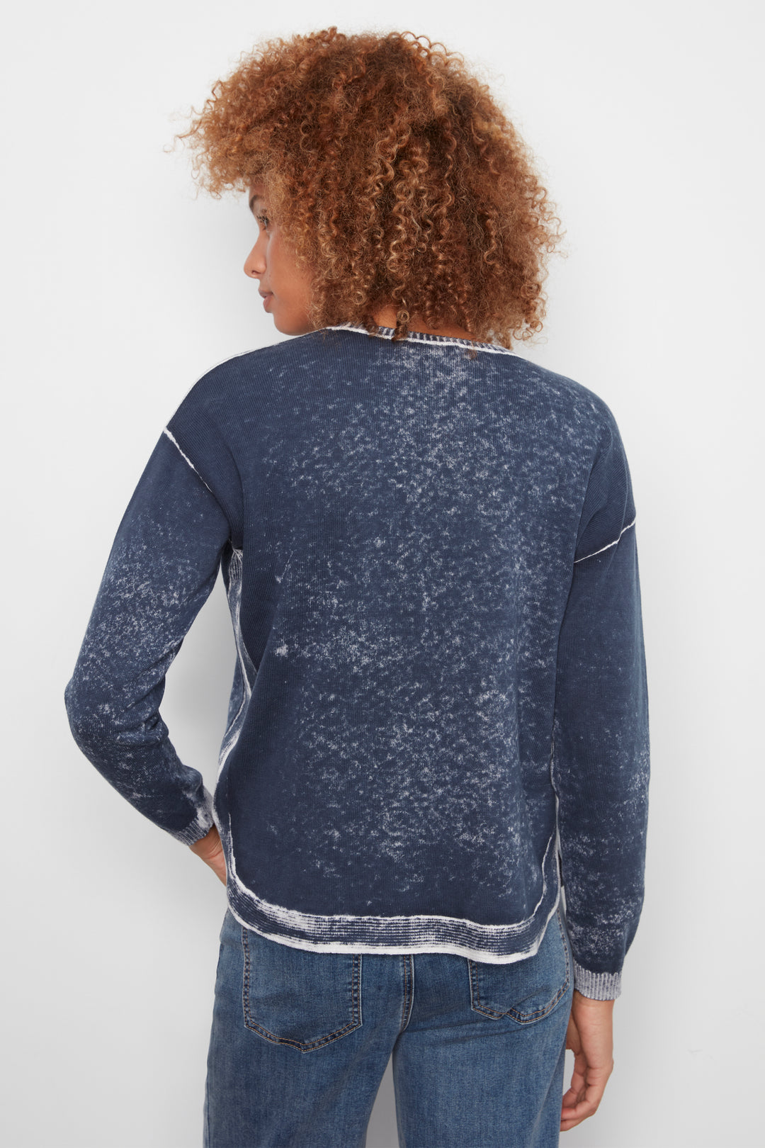 A person shown from the back wearing a dark blue acid-wash long-sleeve crewneck sweatshirt and blue jeans against a plain white background.