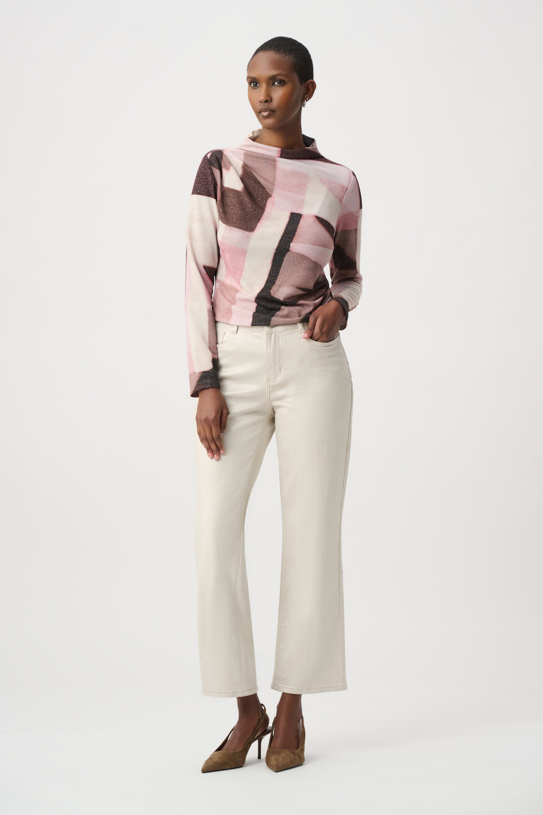Woman wearing a patterned top and white pants on a white background