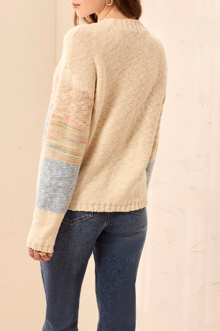 Person wearing a beige sweater with colorful sleeves against a beige background