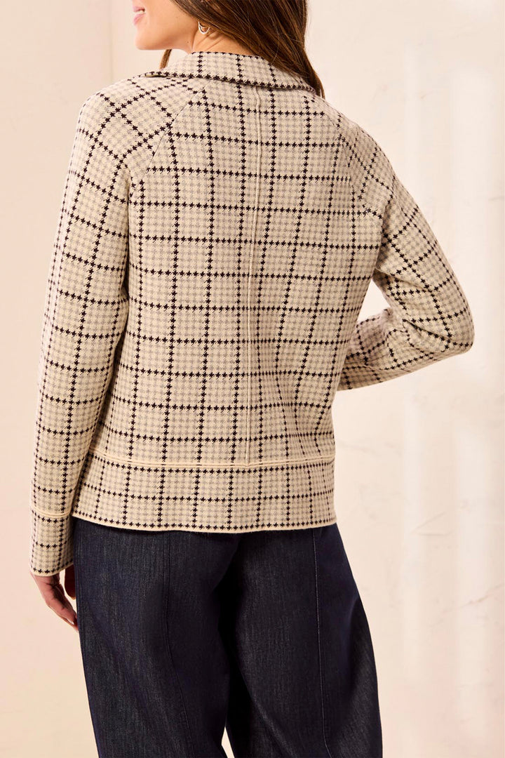 A woman shown from the back wearing a beige and black checkered long-sleeve blazer and dark blue jeans against a light beige background.