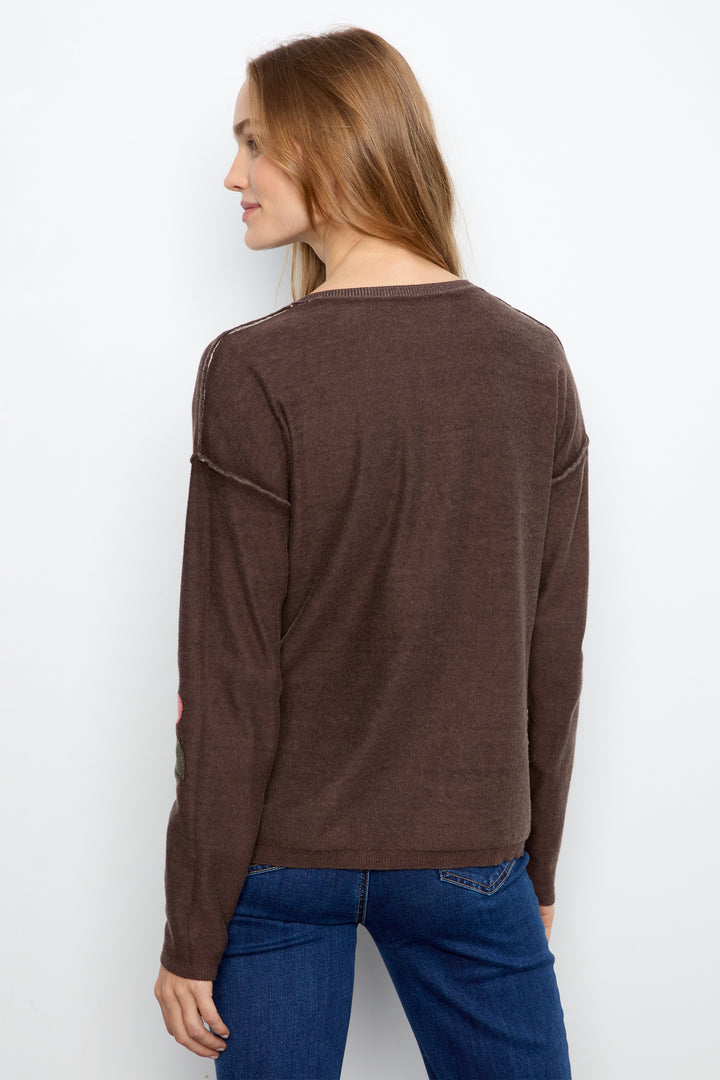 A woman shown from the back wearing a brown long-sleeve knit top and blue jeans against a plain white background.