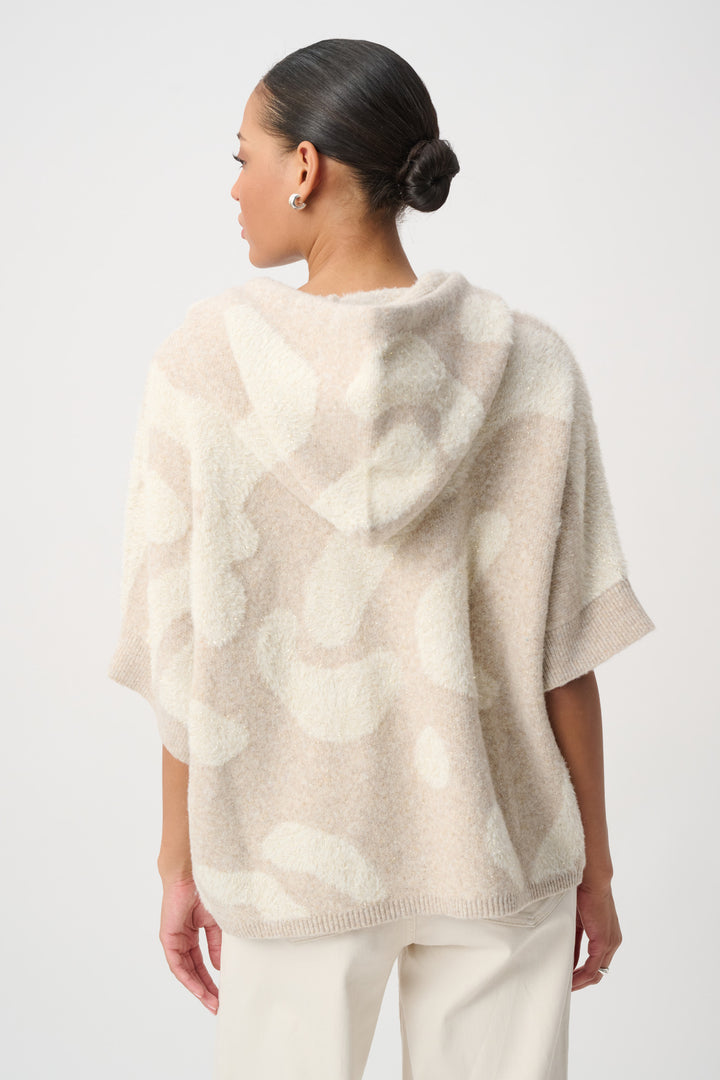 The back view of a woman modelling a beige printed sherpa jacket with hood in front of a white background. 