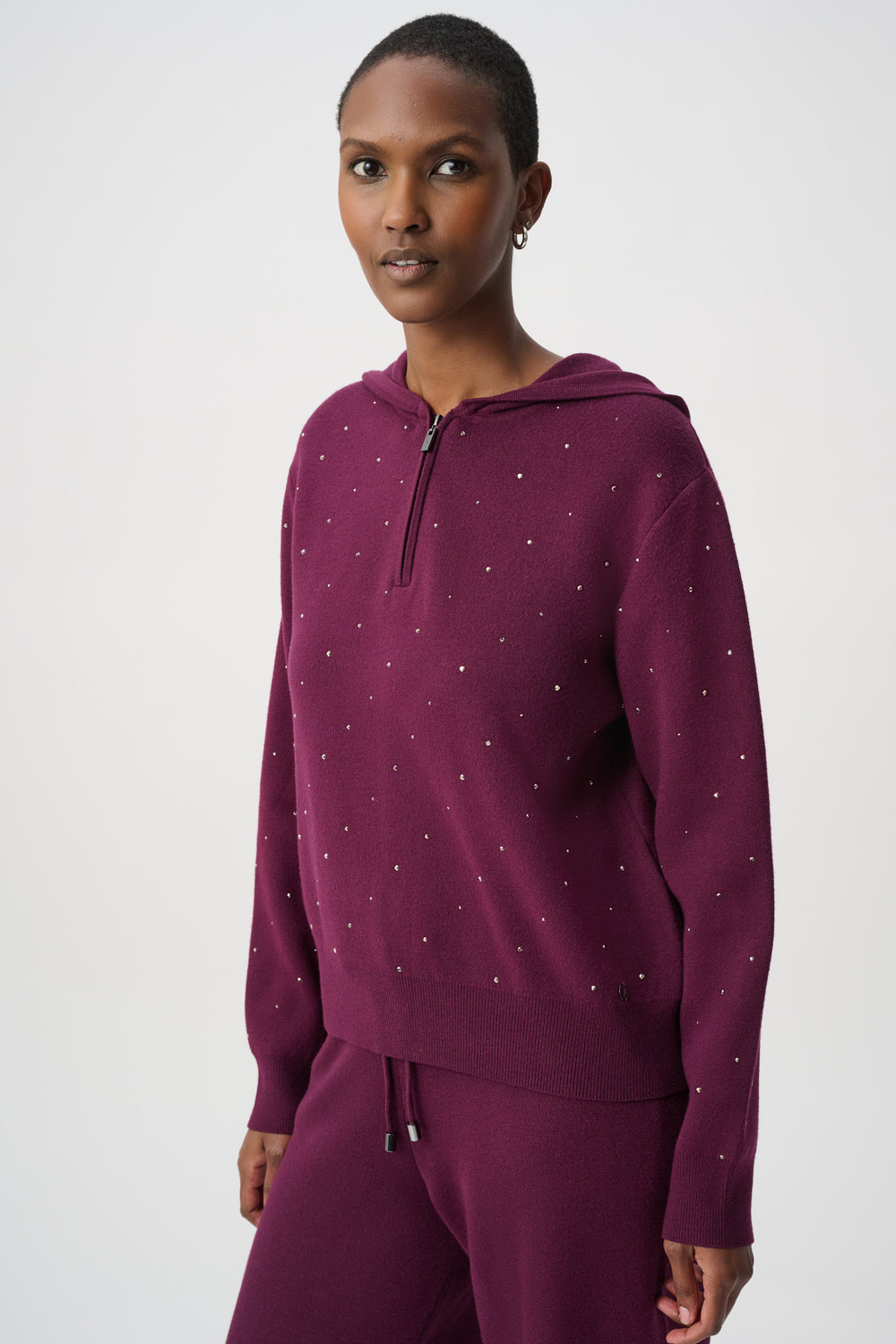 Woman wearing a purple hoodie with  rhinestones on a white background