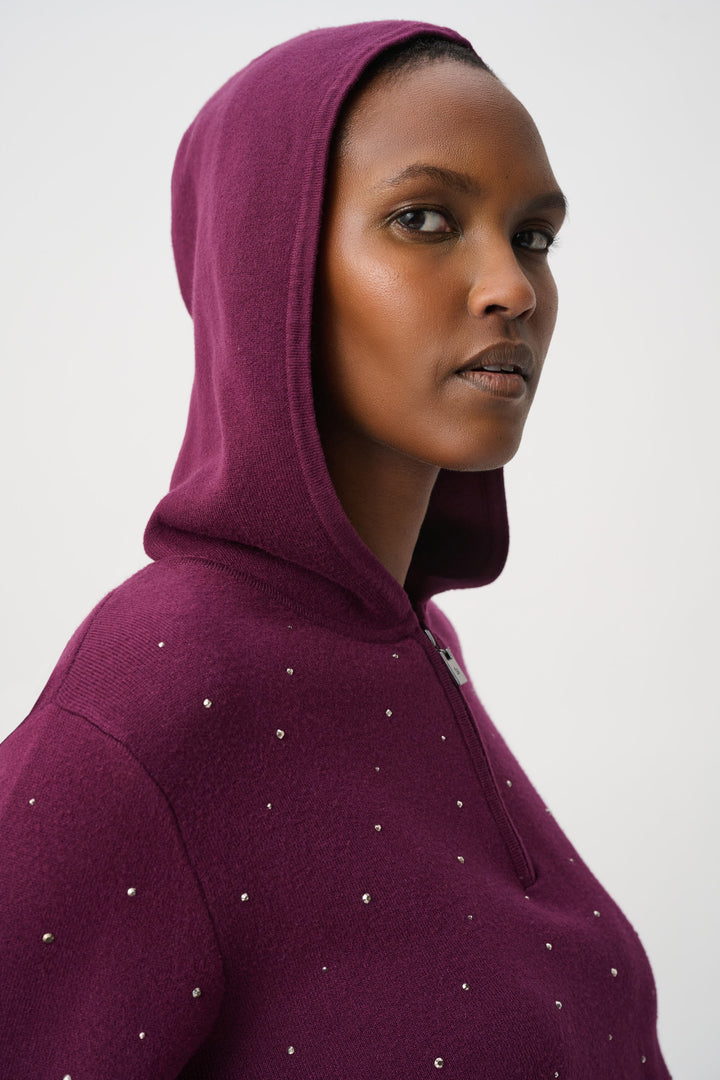 Close up of a woman wearing a maroon hoodie with decorative elements on a white background