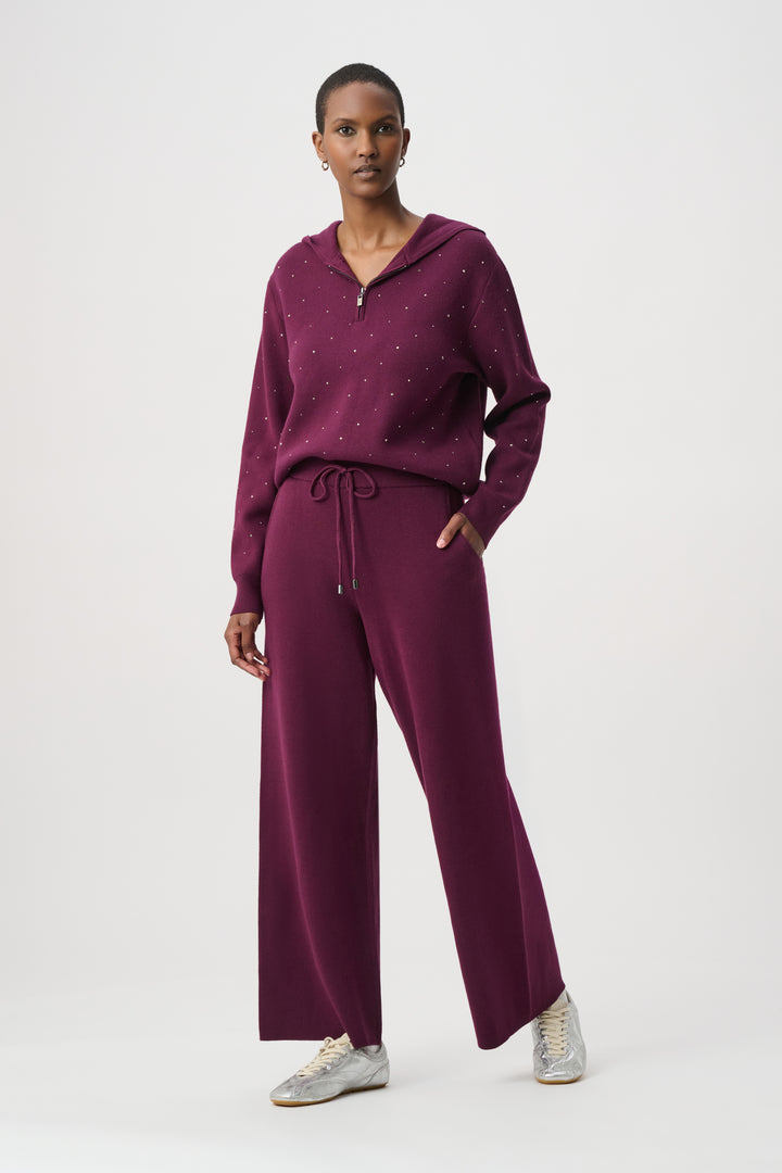Woman wearing a purple outfit with wide-leg pants on a white background