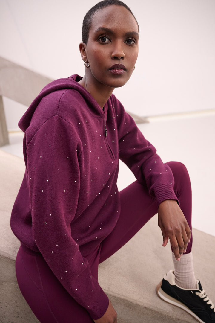 Woman wearing a purple tracksuit sitting on a white surface.