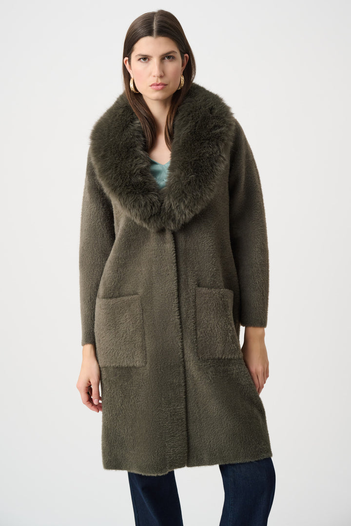 Woman wearing a long olive green coat with a fur collar on a white background