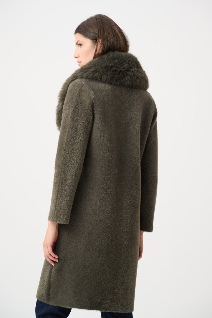 Woman wearing a long olive green coat with fur collar shown from the back on a white background