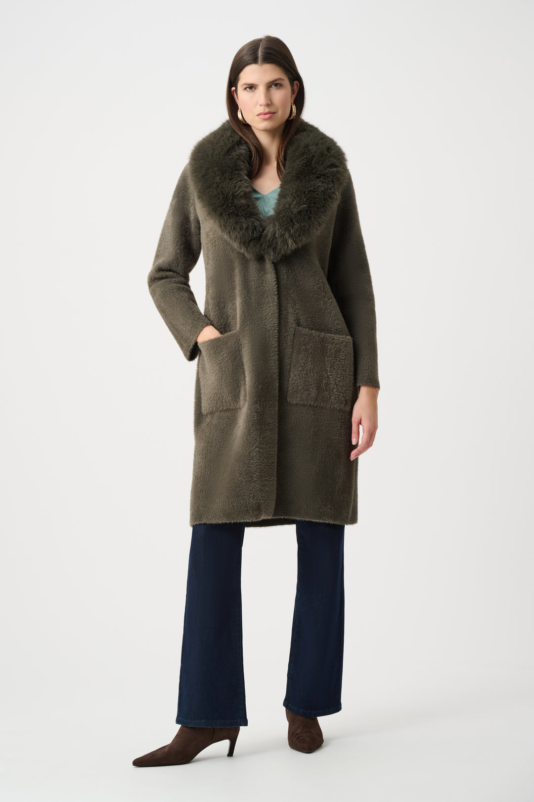 Woman wearing a long olive green coat with fur collar on a white background