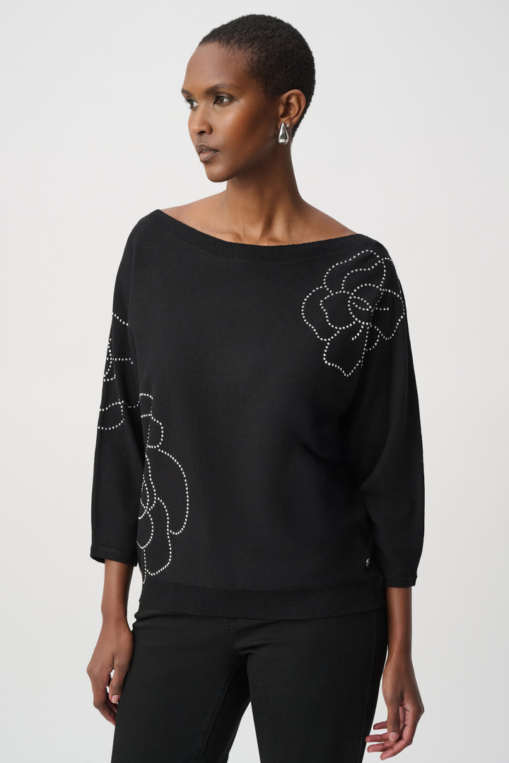 Woman wearing a black top with floral embellishments on a white background
