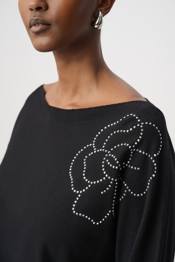 Close up of a woman wearing a black top with floral embellishments on a white background