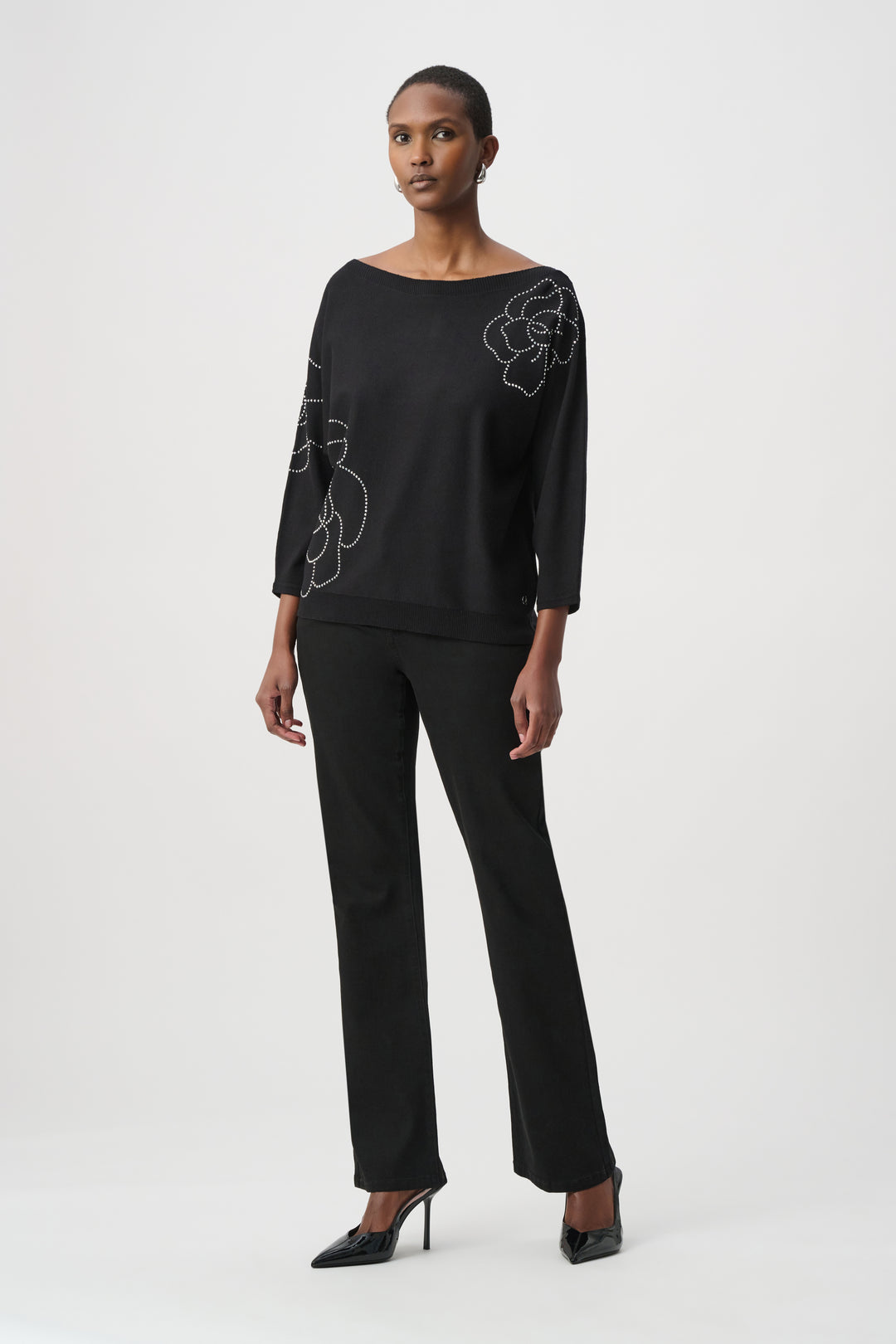 Woman wearing a black outfit with floral embroidery on a white background