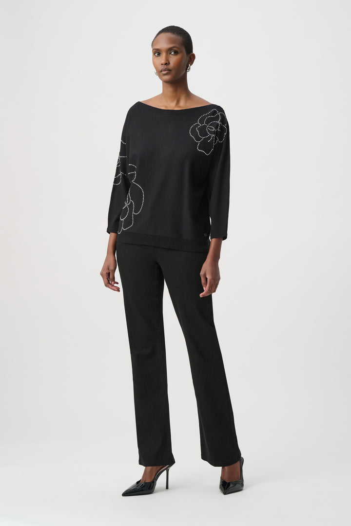 Woman wearing a black outfit with floral embroidery on a white background