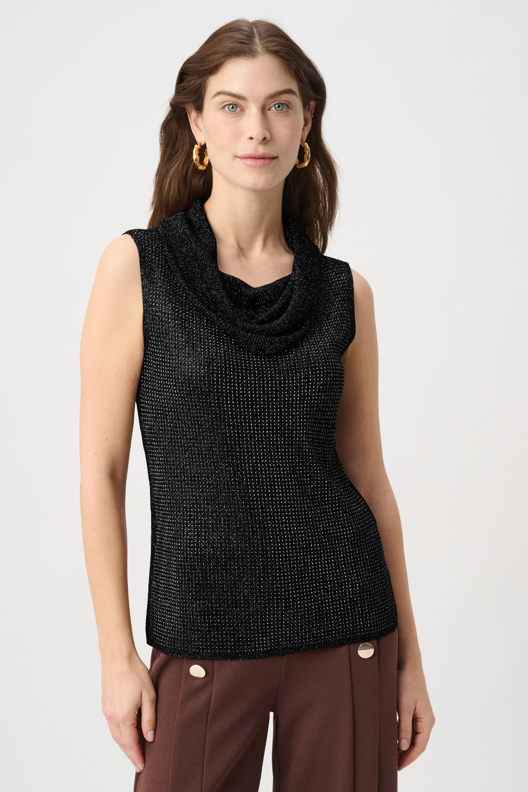 Woman wearing a black sleeveless top with a cowl neckline on a white background