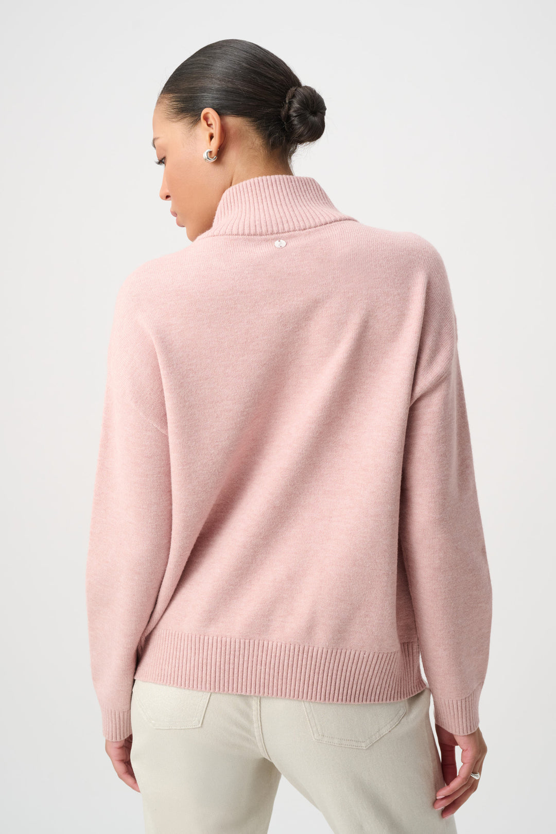 Person wearing a pink sweater on a plain background