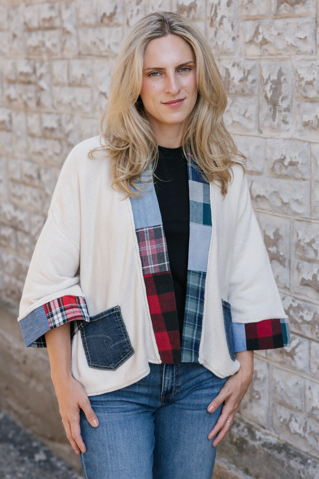 A woman modelling a cream cardigan with denim plaid patchwork details