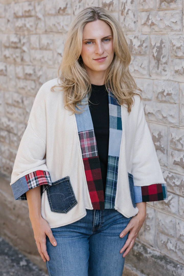 A woman modelling a cream cardigan with denim plaid patchwork details