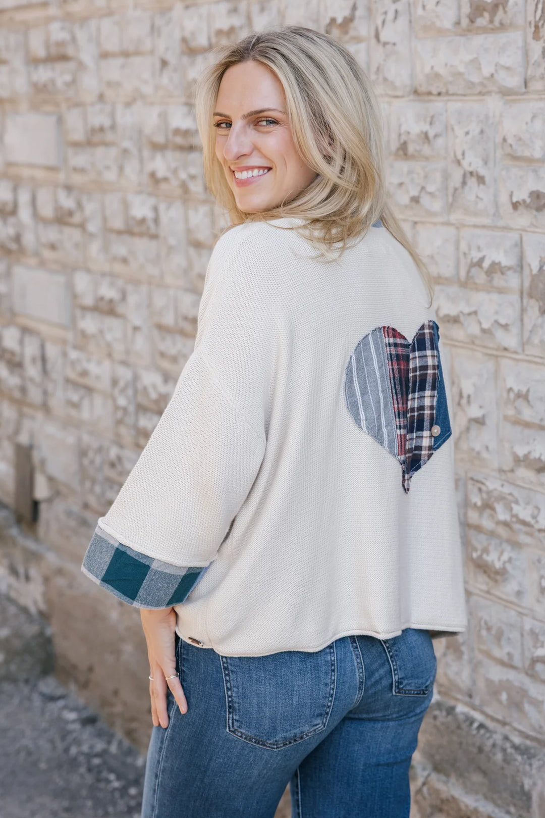 A woman modelling a cream cardigan with denim plaid patchwork details