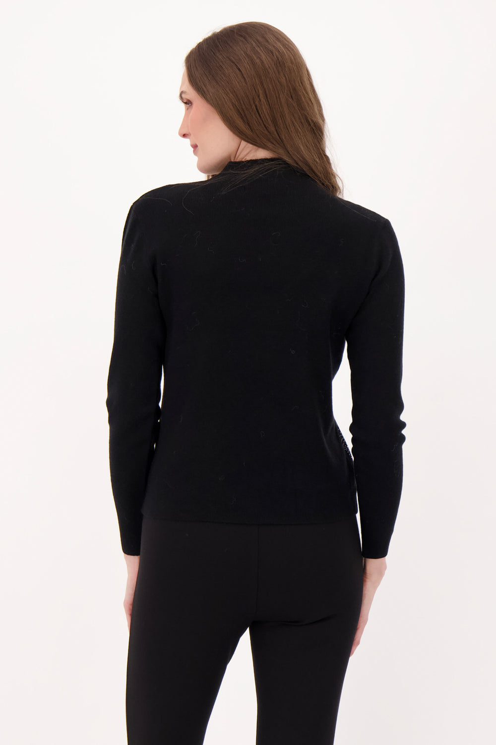 A woman modelling a black sweater with rhinestone embellishments in front of a light grey background. 