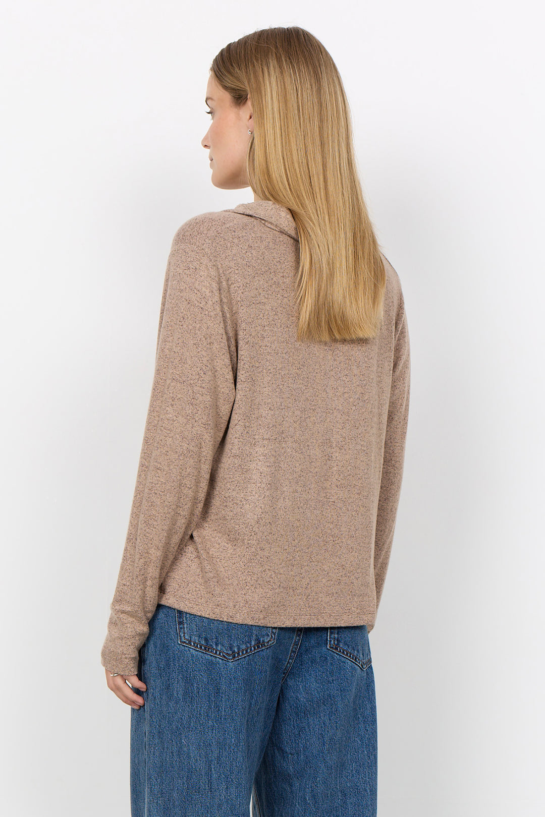A woman modelling a long sleeve polo sweater and jeans in front of a white background. 