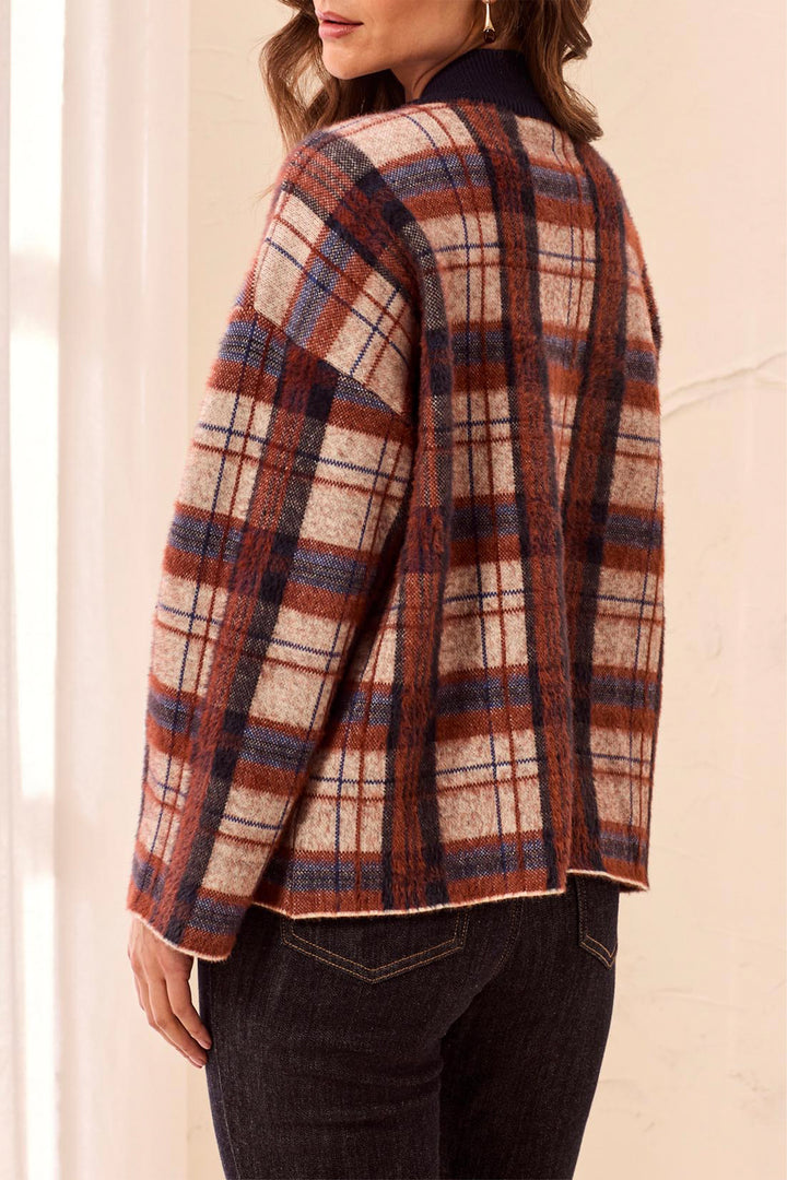 A woman modelling a plaid boxy cardigan in front of a beige background. 