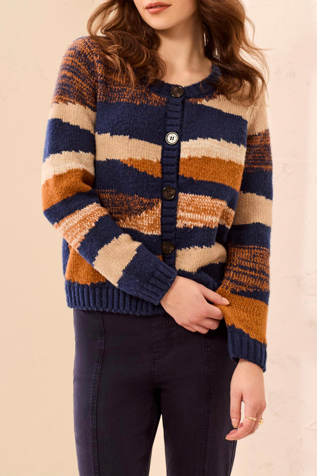 A woman modelling a navy stripe cardigan in front of a beige background. 