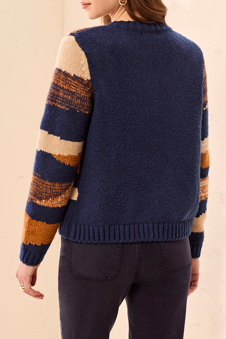 A woman modelling a navy stripe cardigan in front of a beige background. 
