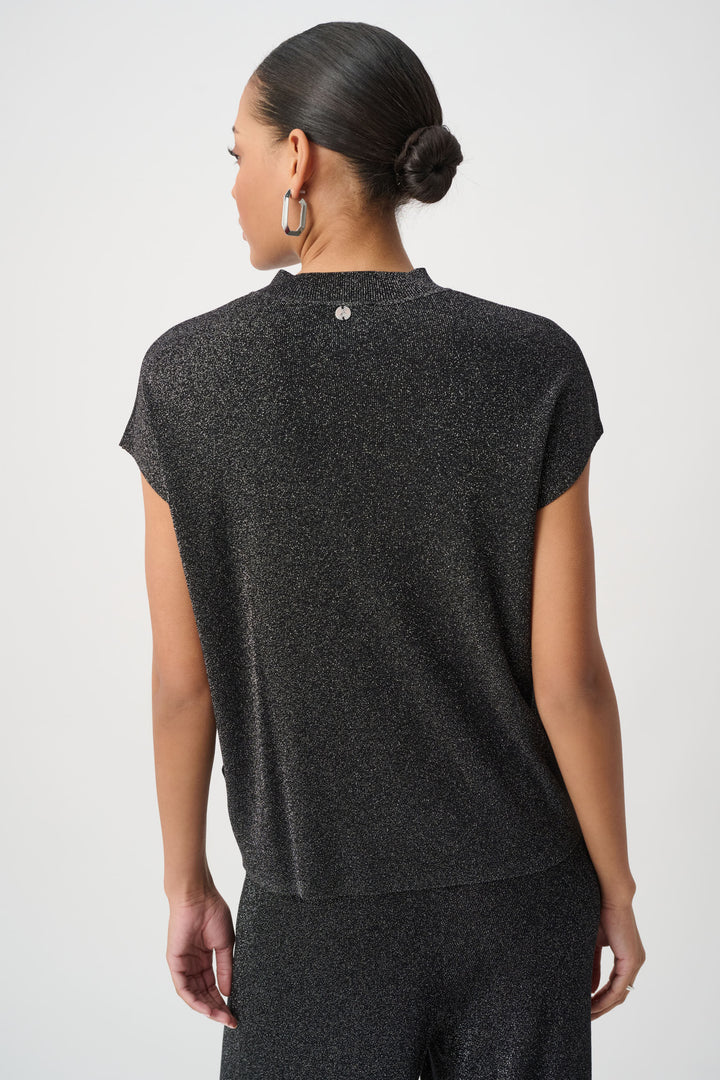 A woman shown from the back modelling a black shimmery t-shirt top with a mock neck and matching pants standing in front of a light grey background. 