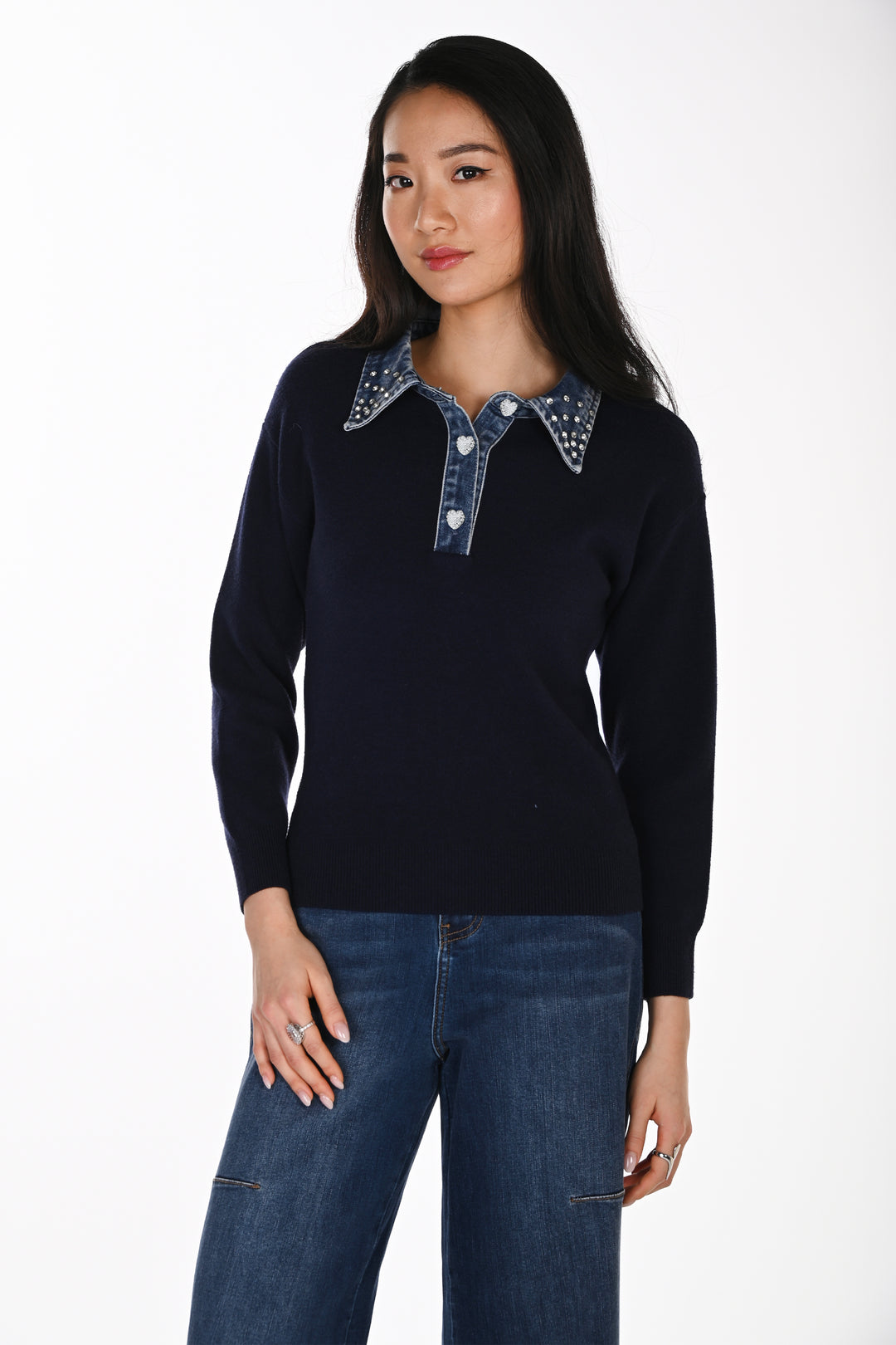 A woman modelling a navy sweater with a denim and rhinestone collar standing in front of a white background. 