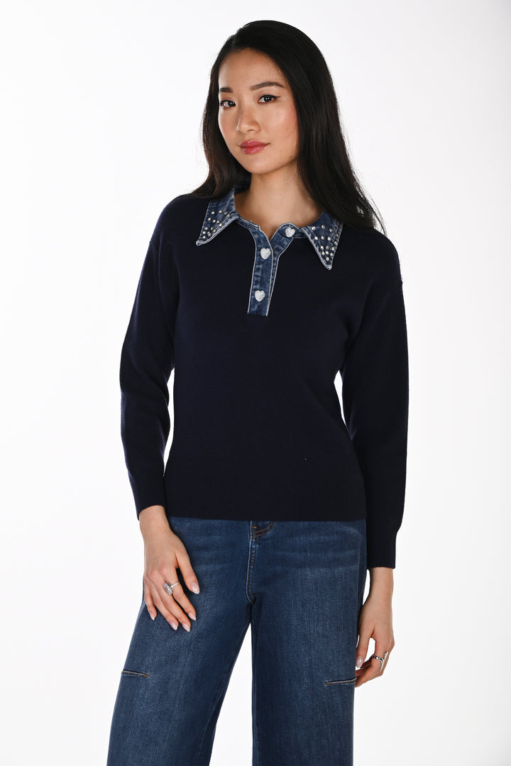 A woman modelling a navy sweater with a denim and rhinestone collar standing in front of a white background. 