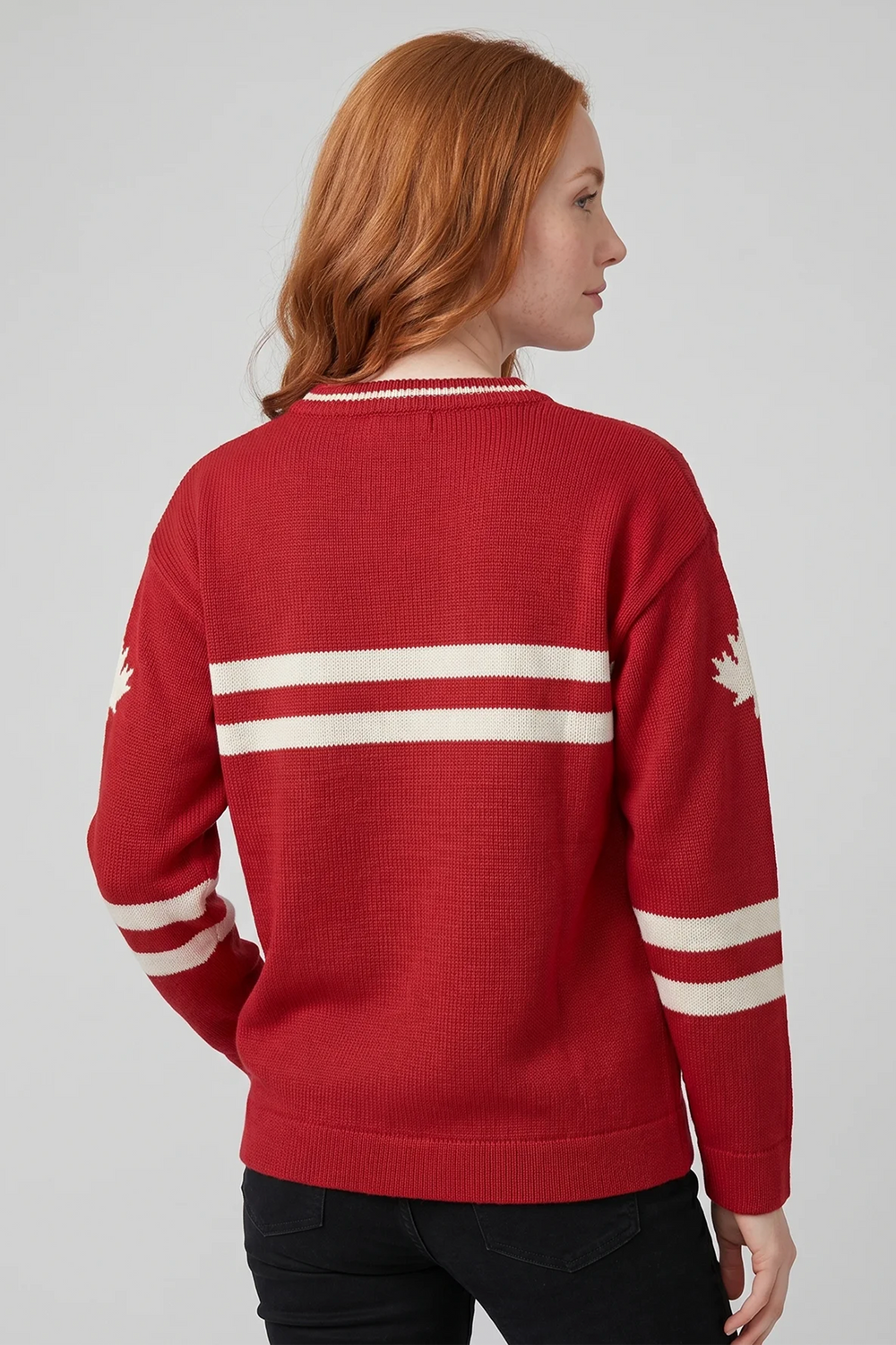 A woman shown from the back modelling a red hockey jersey style sweater with stripes across the back and a maple leaf on the sleeve. 