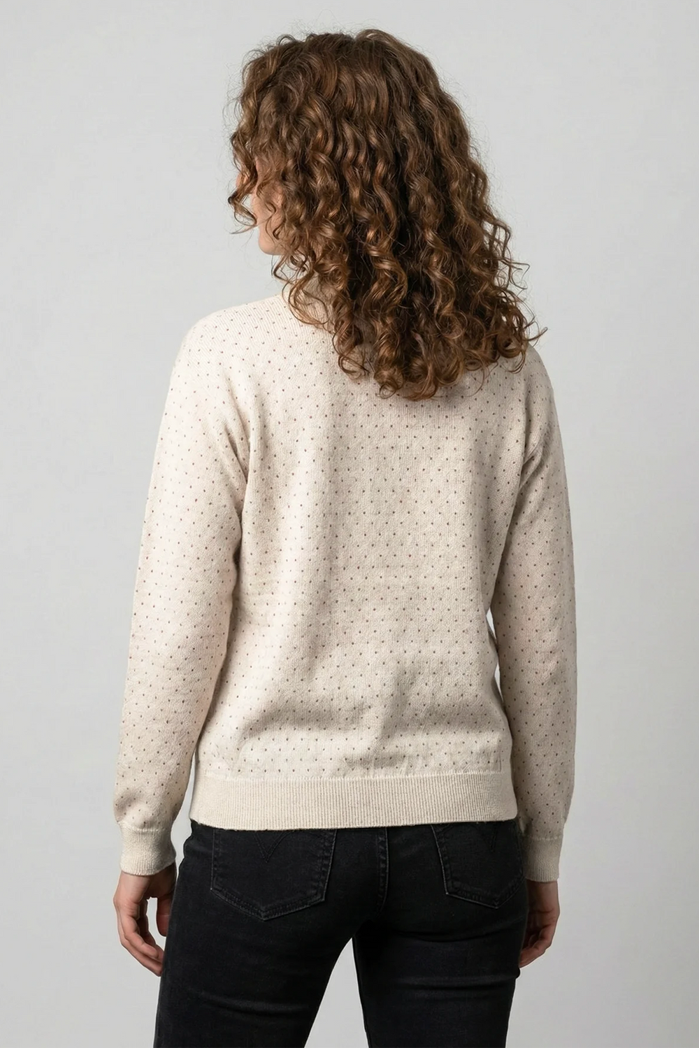A woman shown from the back modelling a beige sweater with red polka dots. 