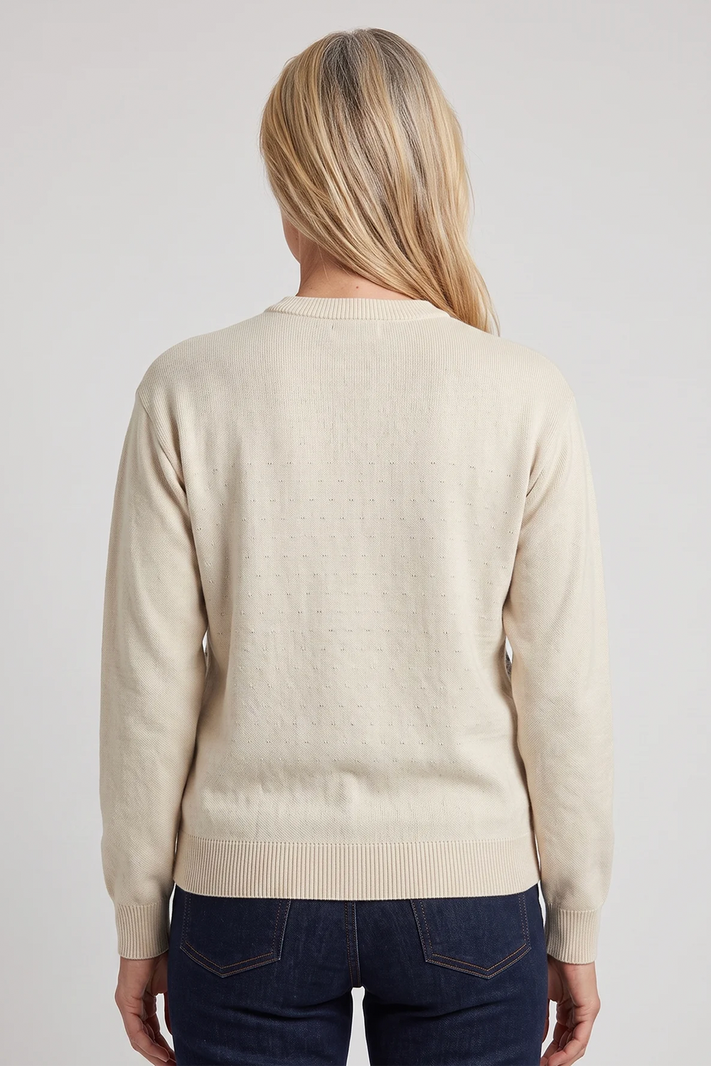 A woman shown from the back wearing a beige long sleeve cotton sweater. 