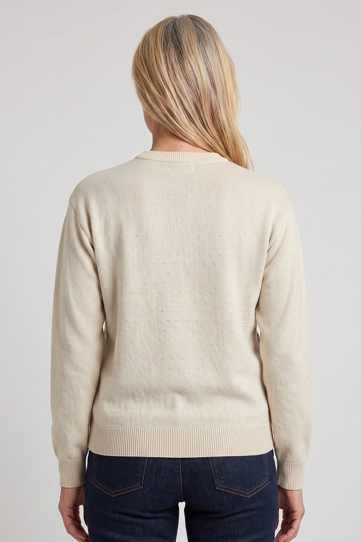 A woman shown from the back wearing a beige long sleeve cotton sweater. 