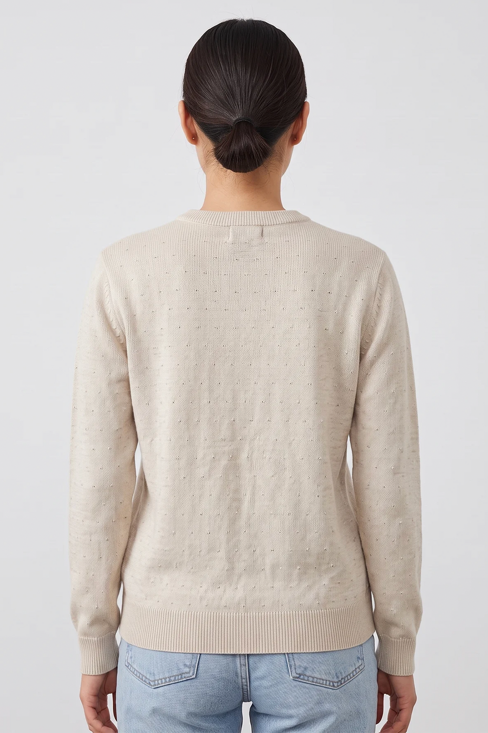 A woman shown from the back wearing a beige long sleeve cotton sweater. 