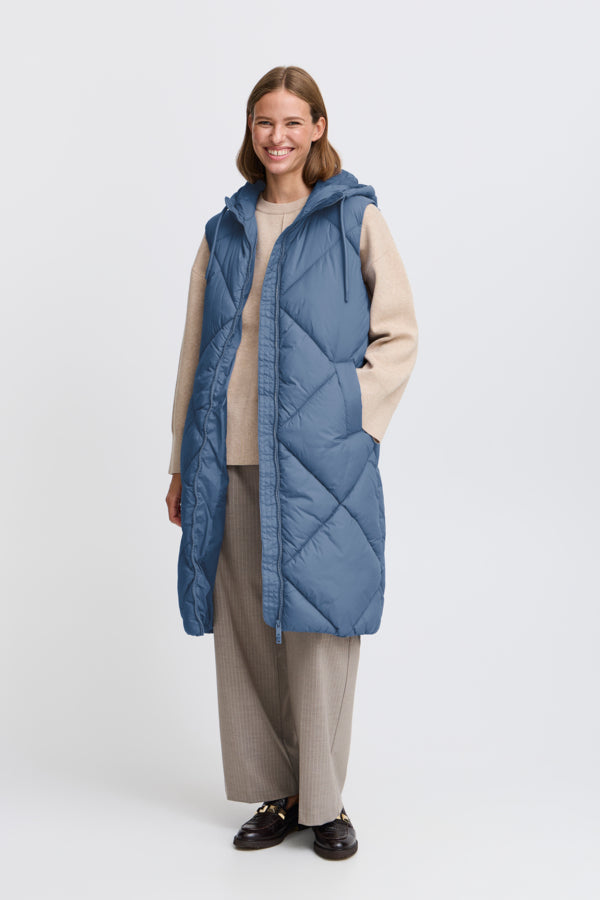 B. Young Fall 2024 Made from eco-friendly recycled fabric, this long vest boasts a large quilted pattern and thick yet light padding for ultimate comfort. The soft woven fabric comes in three stunning colours and features front button pockets and a hood with drawstring.